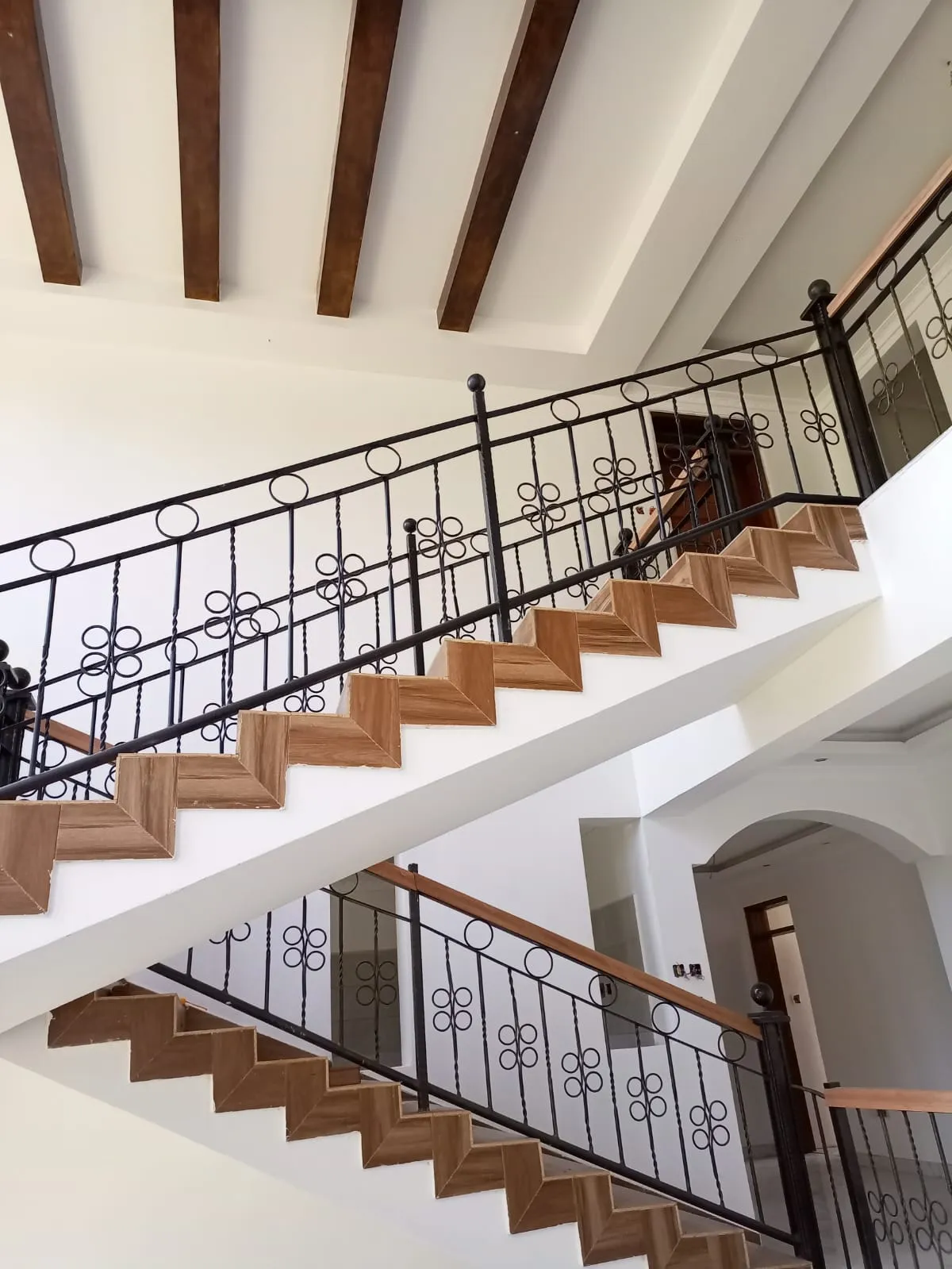 Completed staircase at a Quantech project in Karen, with timber treads, wrought-iron balustrade and exposed ceiling beams